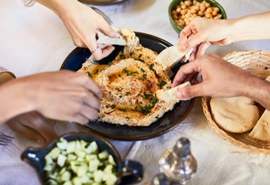 Grupo de amigos compartiendo un hummus con pan pita. 