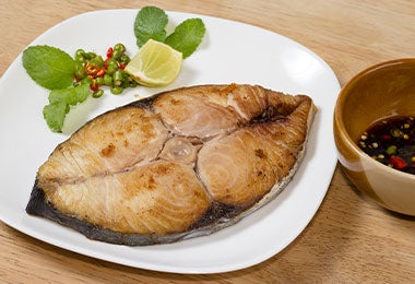 Preparación con aceite de pescado, chiles picados, rodaja de limón y cuenco con salsa oscura