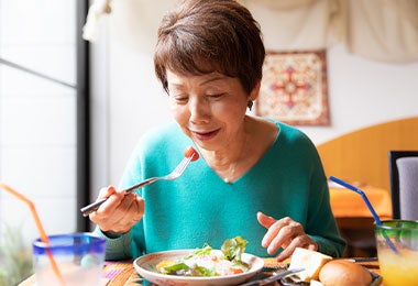 Mujer mayor disfruta una ensalada, reflejando una elección saludable dentro de los hábitos de alimentación en el adulto mayor