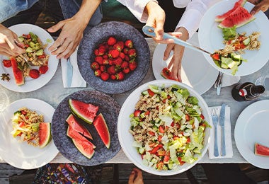 Vista superior de un almuerzo con frutas y pasta que representa la alimentación saludable y no saludable