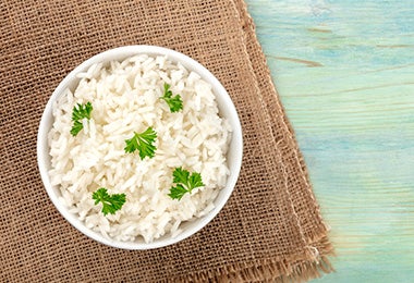 Arroz basmati en un tazón con hojitas de cilantro sobre un mantel café.