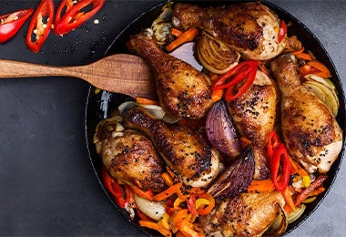 Preparación de bandeja de pollo que incluye achiote con algunas verduras salteadas como pimentón y cebolla