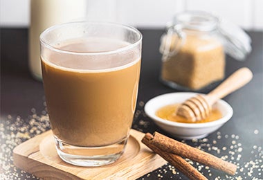 Bebida caliente con leche, café, miel y azúcar morena sobre una superficie negra