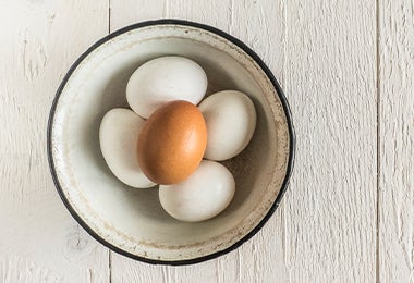 Tazón con tres huevos cocidos sin cáscara y uno con cáscara.