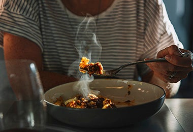 Mujer comiendo pasta de noche