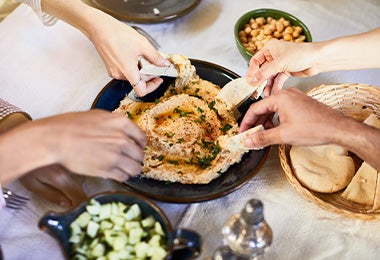 Un grupo de personas compartiendo hummus con pan pita, un clásico de la comida libanesa.