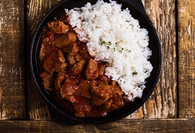  Arroz blanco y carne, comidas fáciles de hacer, servidos en un plato negro. 