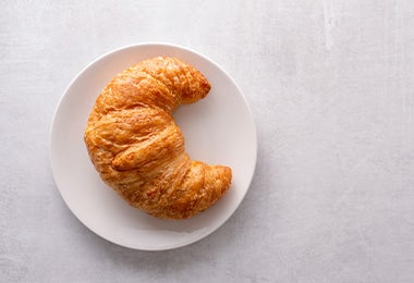 Croissant de la repostería francesa en un plato con un fondo blanco.