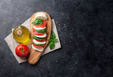 Vista superior de una ensalada caprese con rebanadas de tomate, queso mozzarella fresco, hojas de albahaca y aceite de oliva, reflejando alimentos con vitamina D ideales