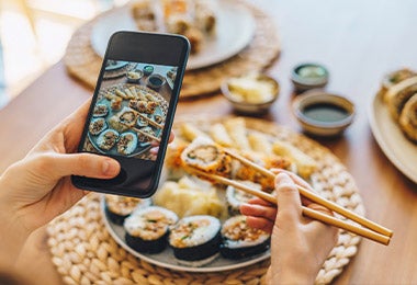 Una persona celebrando el Día Internacional del Sushi tomando una foto desde su celular