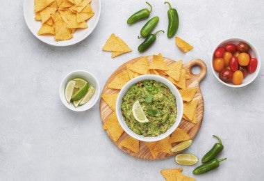 Bowl de guacamole con totopos, tomatillos, chile y limón para comer con anchoas.
