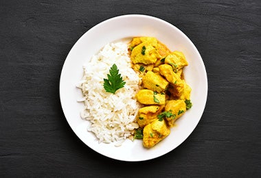 Un pollo al curry con arroz blanco.
