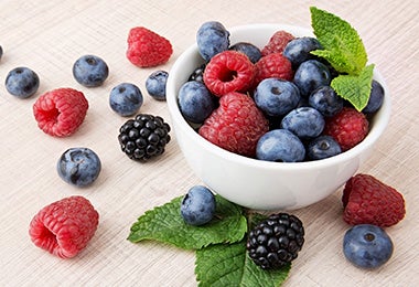 Un bowl pequeño lleno de arándanos, moras y frambuesas.