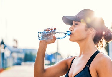 Una mujer tomando agua después de hacer ejercicios para principiantes 