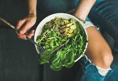 Una mujer utilizando verduras verdes en su plan de alimentación