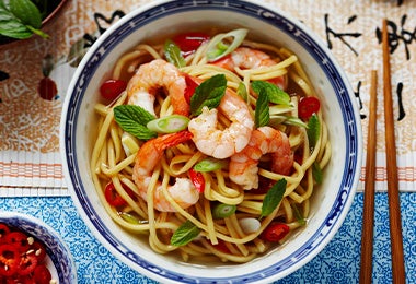 Noodles con camarones y especias, servidos en un plato de origen asiático. 