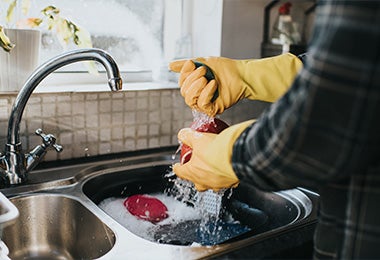 Persona ahorrando agua mientras lava su propia loza