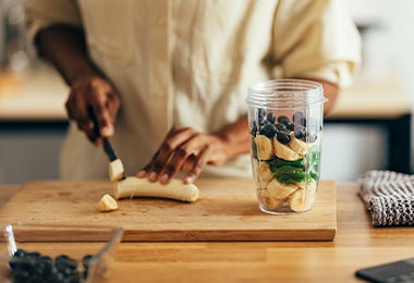 Una persona preparando un batido de frutas y verduras en su rutina de vida activa