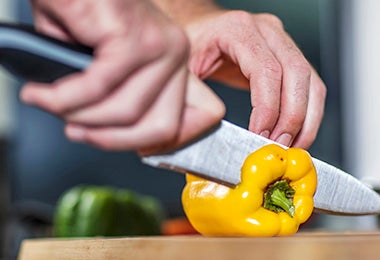 Pimiento amarillo siendo cortado para rellenar en una parrillada vegetariana