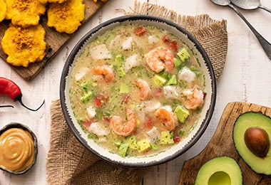 Plato de caldo de pescado con camarones, chiles, plátano y aguacate