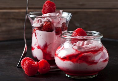  Un postre en vaso con frutos rojos, frutos secos y crema batida. 