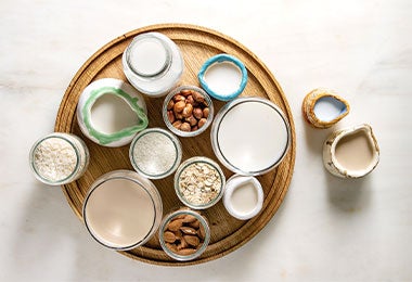 Bandeja con pequeños recipientes llenos de almendras y jarras y vasos con bebida de almendras.