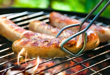 Salchichas cocinándose en la parrilla como alimentos ultraprocesados