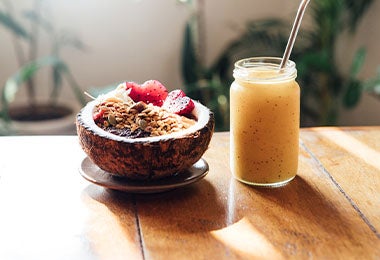 Smoothie de mandarina con maracuyá y un bowl de fruta servido en cáscara de coco. 