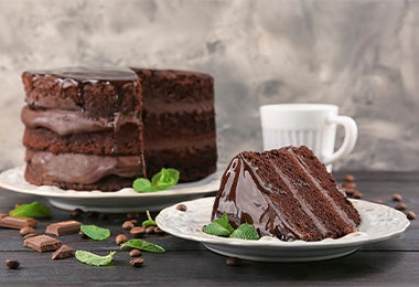 Torta de chocolate preparada con cacao y cubierta con crema en un plato blanco con hojas aromáticas