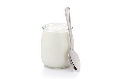 Recipiente de vidrio con yogurt griego y cuchara 