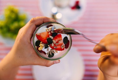 Una persona comiendo un yogurt griego después de hacer ejercicios para principiantes