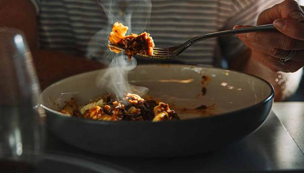 Una persona comiendo un plato de pasta, una de las comidas fáciles de hacer. 