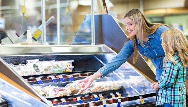 Mujer en supermercado en sección de alimentos congelados 