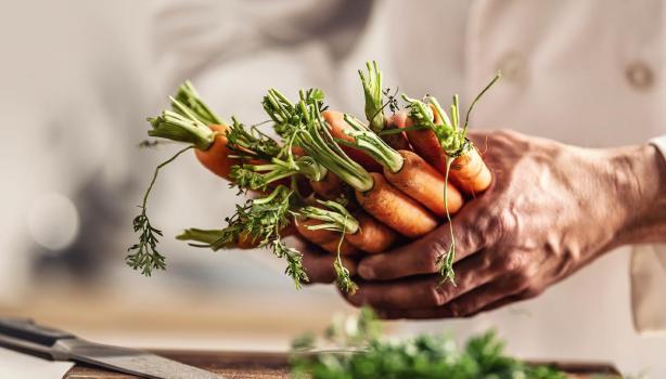 Persona cocinando con zanahorias y creando su plantilla de menú semanal.