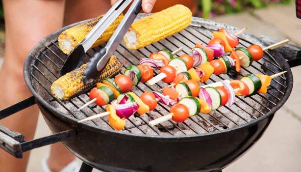 Asador con vegetales y pinzas de cocina 
