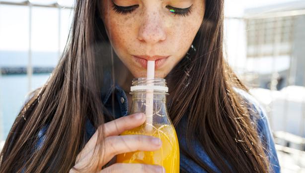 Mujer bebiendo un refrescante jugo de zanahoria con limón.