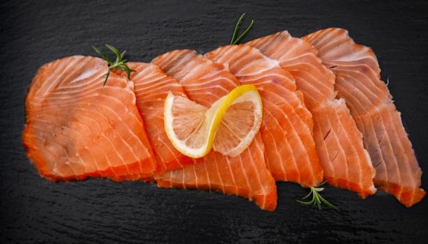 Pequeños trozos de salmón ahumado frío sobre fondo negro.