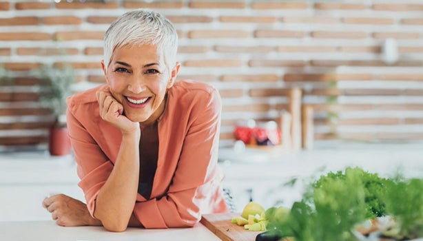 Mujer con tabla a su lado llena de fruta en trozos, representando un momento cotidiano de alimentación en el adulto mayor
