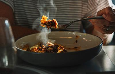 Una persona comiendo un plato de pasta, una de las comidas fáciles de hacer. 