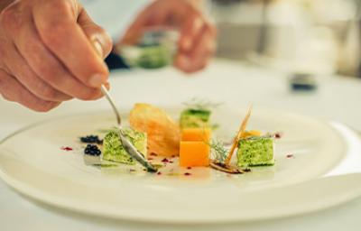 Una persona emplatando con una cuchara una comida con caviar