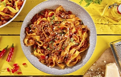 Pasta a la boloñesa con carne, queso parmesano y hierbas aromáticas sobre un fondo amarillo Pasta a la boloñesa con carne, queso parmesano y hierbas aromáticas sobre un fondo amarillo