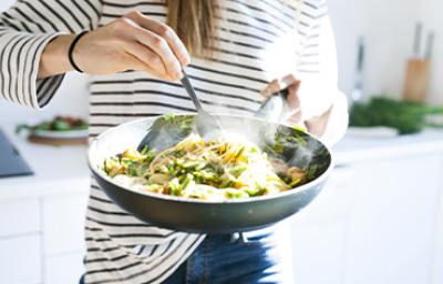 Una persona cocinando su comida con menos de 5 ingredientes en una sartén Una persona cocinando su comida con menos de 5 ingredientes en una sartén