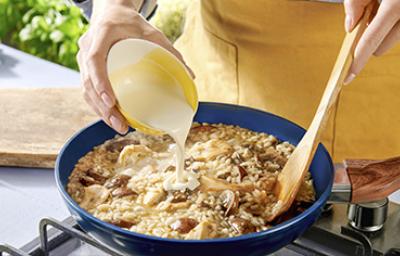 Una persona preparando una receta de cocción lenta con hongos, crema y arroz Una persona preparando una receta de cocción lenta con hongos, crema y arroz