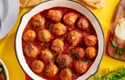 Albóndigas con salsa putanesca en una sartén cebollas y cilantro Albóndigas caseras en salsa putanesca servidas en una sartén con cebollas y cilantro