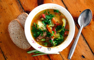 Uso de achiote en la preparación de una sopa de verduras y carne, acompañada con pan en rebanadas