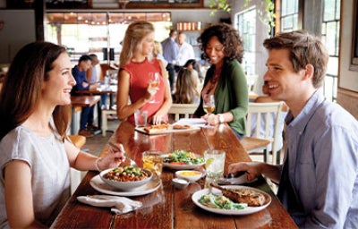 Un anfitrión habla con sus invitados mientras comen