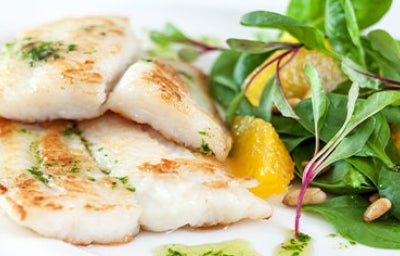 Uso de aceite de pescado en un plato de varios filetes blancos, acompañados de una ensalada