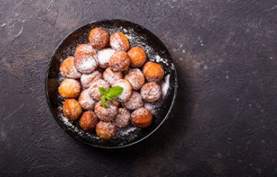 Buñuelos de yuca espolvoreados con azúcar en plato negro