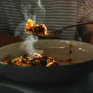 Una persona comiendo un plato de pasta, una de las comidas fáciles de hacer. 
