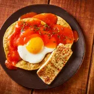 Un desayuno con huevo, tortillas y salsa.